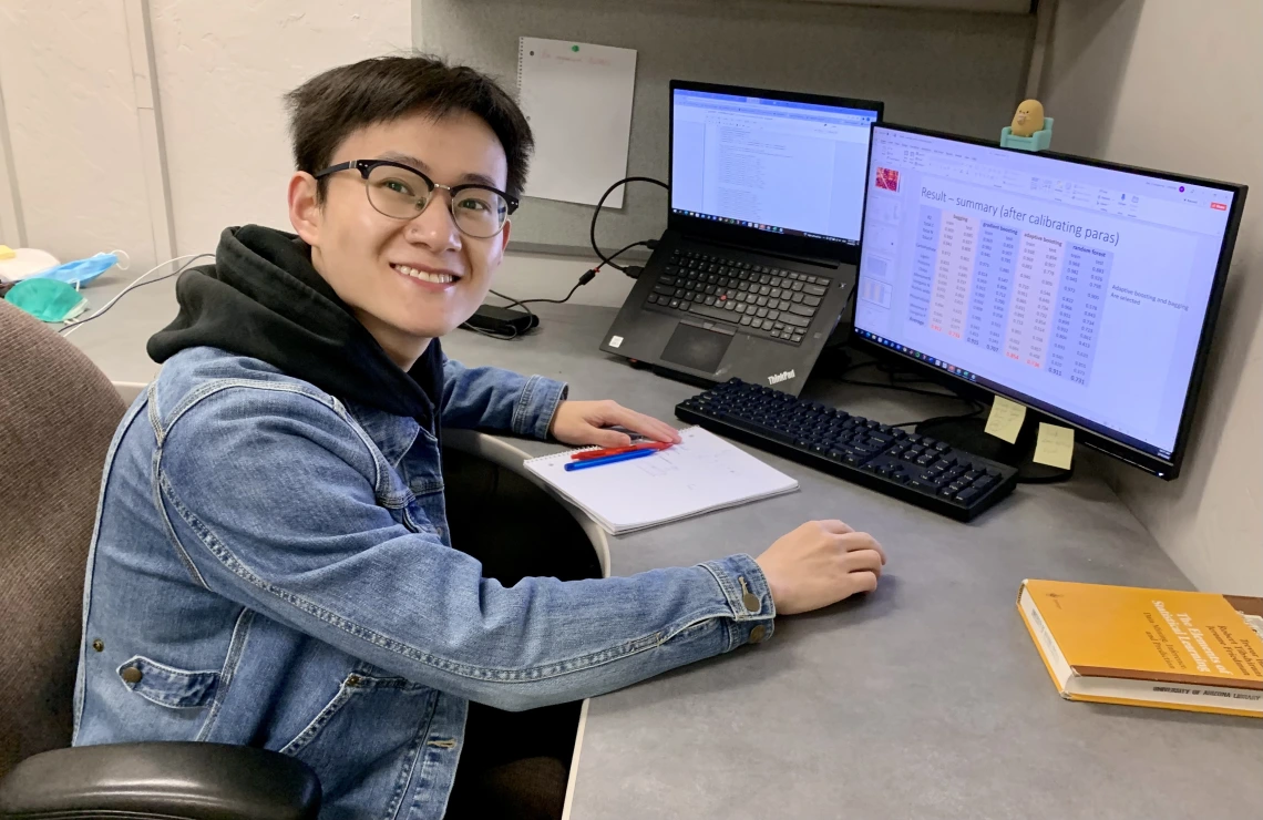 Changpeng works compiling research data at his desk.